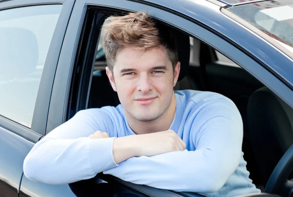 Jovem positivo sentado em seu carro — Fotografia de Stock