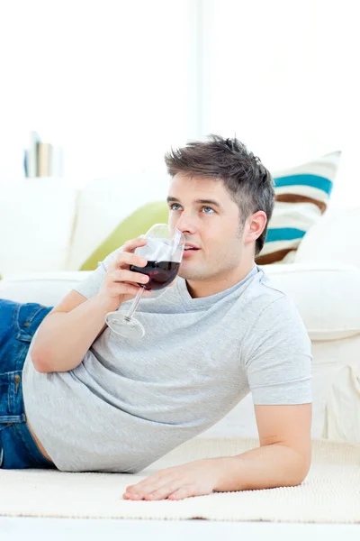 Pozytywny człowiek młody picia wina w pokoju dziennym — Zdjęcie stockowe