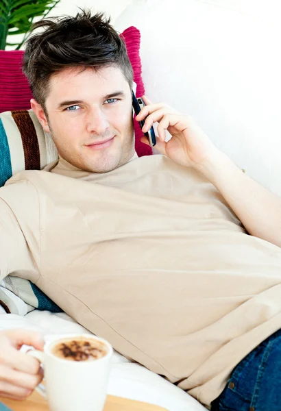 Pohledný mladý muž mluví telefonu doma — Stock fotografie
