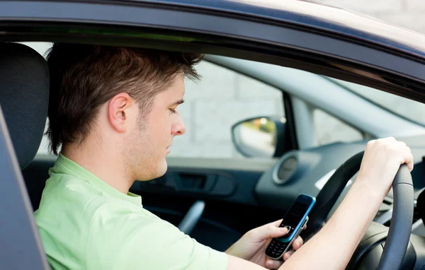 Geconcentreerd man verzenden van een tekst in zijn auto zit — Stockfoto