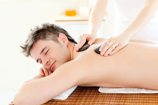 Charming man enjoying a massage with hot stone — Stock Photo, Image