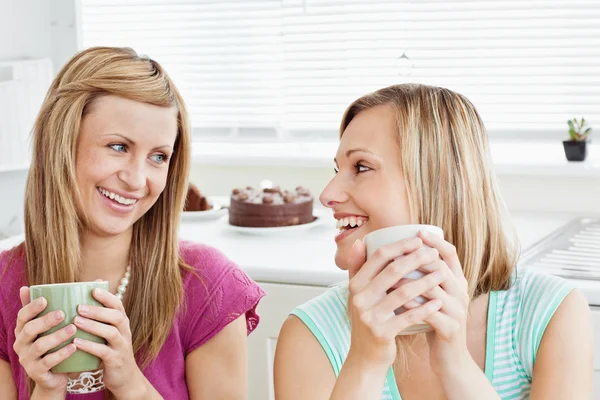 Delighted female friends holding a cup of coffee at home — Stock Photo, Image