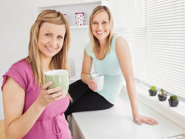 Retrato de duas mulheres felizes segurando xícaras de café em casa — Fotografia de Stock