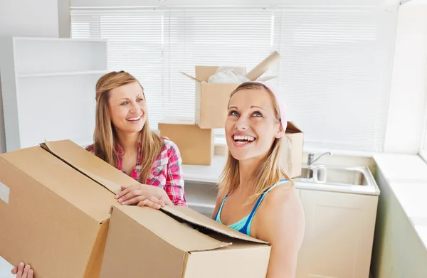 Två strålande kvinnor bära lådor hemma — Stockfoto