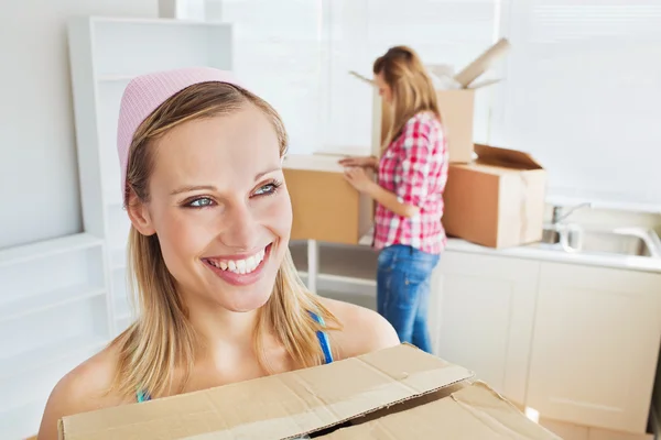 Dos mujeres alegres llevando cajas en casa —  Fotos de Stock