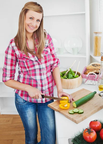 Mulher alegre cortando pimenta e pepino em casa — Fotografia de Stock