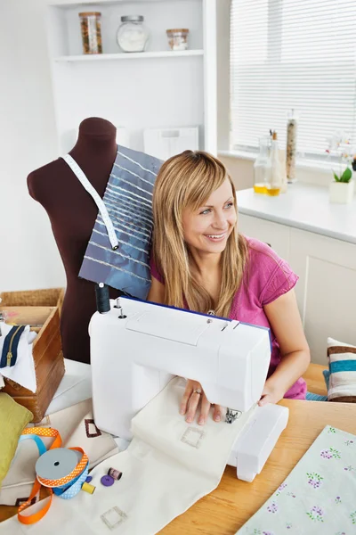 Delighted woman sewing clothes in the kitchen — Stock Photo, Image