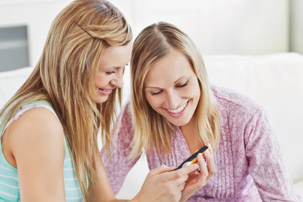 Glada väninnor med hjälp av en mobiltelefon hemma — Stockfoto