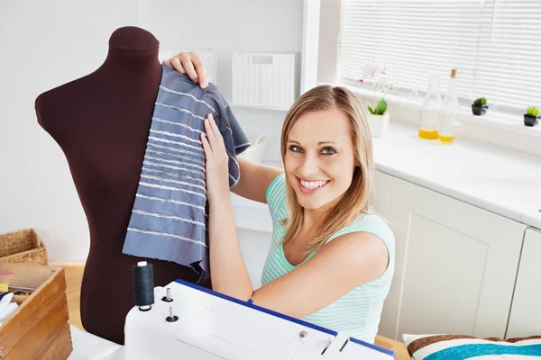 Веселая женщина шьет одежду дома — стоковое фото