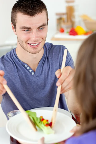 Ευτυχισμένος άνθρωπος βάζοντας σαλάτα σε ένα πιάτο δείπνο με του girlfr — Φωτογραφία Αρχείου