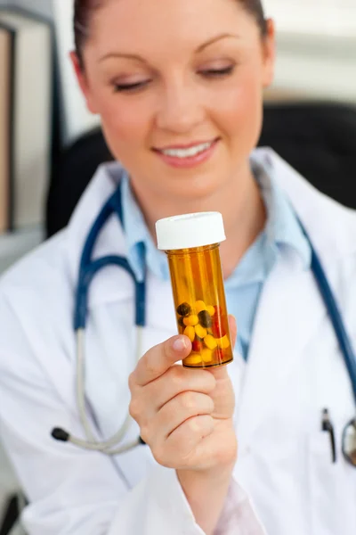 Сяючий молода жінка-лікар дивиться на таблетки — стокове фото