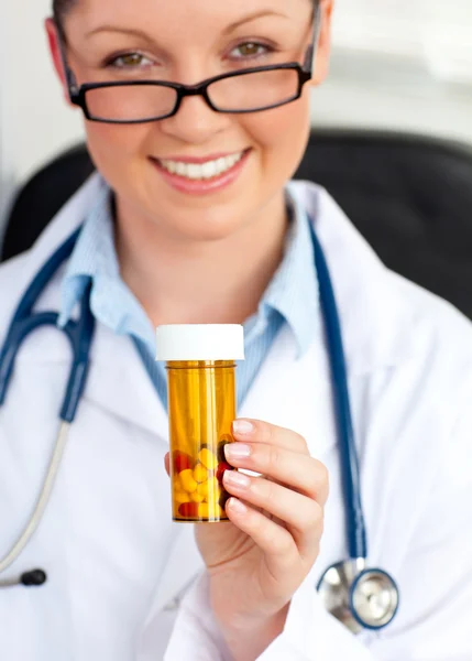 Gloeiende jonge vrouwelijke arts pillen houden — Stockfoto