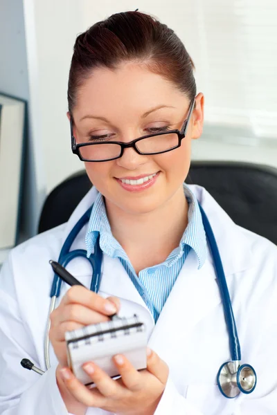 Уверенная женщина-врач улыбается в камеру, держа блокнот — стоковое фото