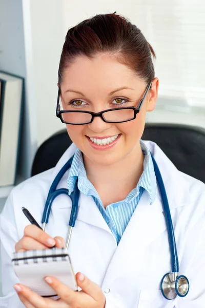 Auto-assicurato medico femminile sorridente alla fotocamera che tiene un notep — Foto Stock