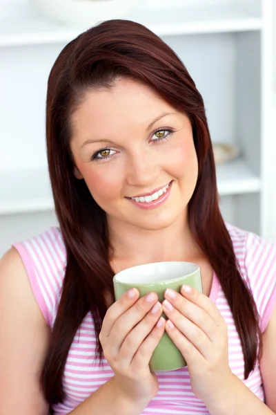 Cheerful woman holding a cup of coffee in the kitchen — Stock Photo, Image