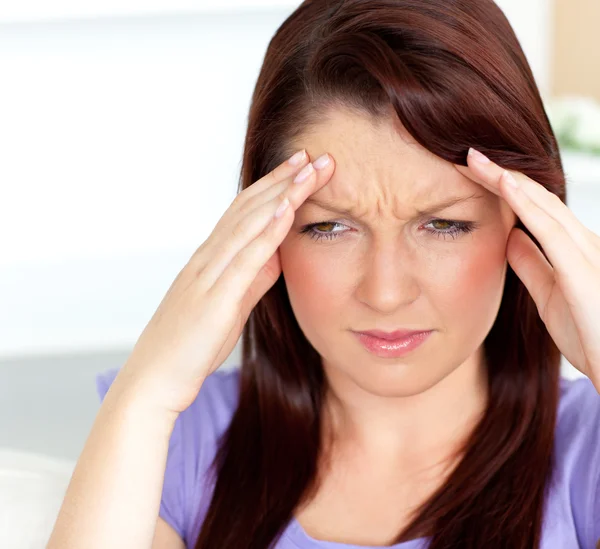 Удрученная женщина с головной болью сидит в гостиной — стоковое фото