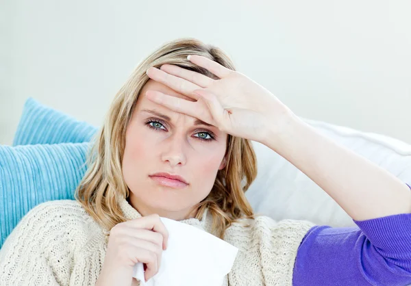 Diseased woman lying on a sofa with tissues and feeling her temp — Stock Photo, Image