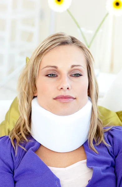 Aantrekkelijke vrouw dragen neckbrace liggen op een sofa — Stockfoto