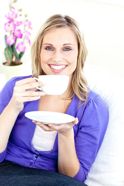 Веселая молодая женщина, держащая чашку кофе на диване — стоковое фото