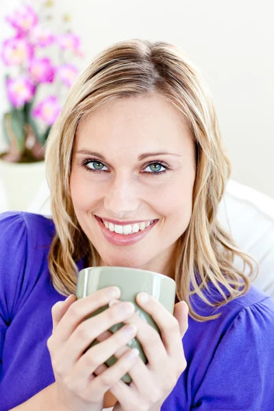 ソファの上にコーヒーのカップを保持してうれしそうな若い女性 — ストック写真