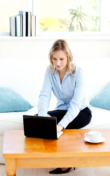 Femme d'affaires rayonnante en utilisant son ordinateur portable assis sur un canapé — Photo
