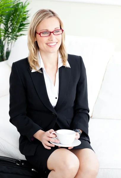 Delighted businesswoman wearing glasses drinking coffee sitting — Stock Photo, Image