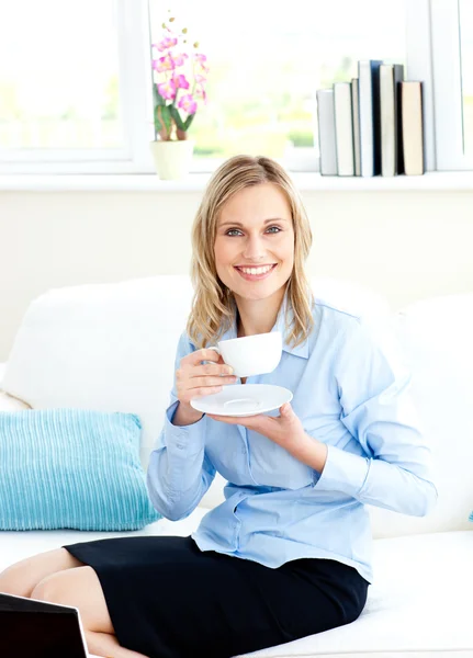 Sorridente donna d'affari che beve caffè seduta su un divano — Foto Stock