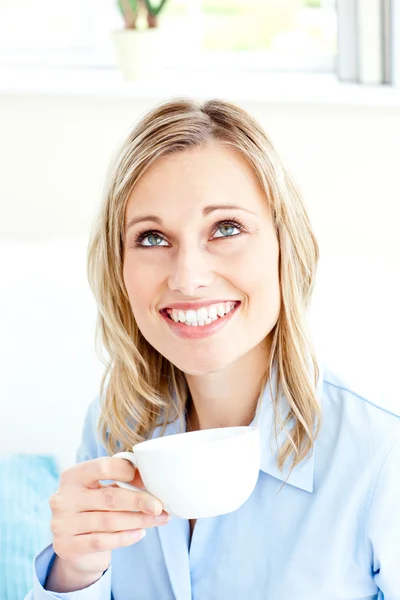Bright businesswoman drinking coffee sitting on a sofa at home — Stock Photo, Image
