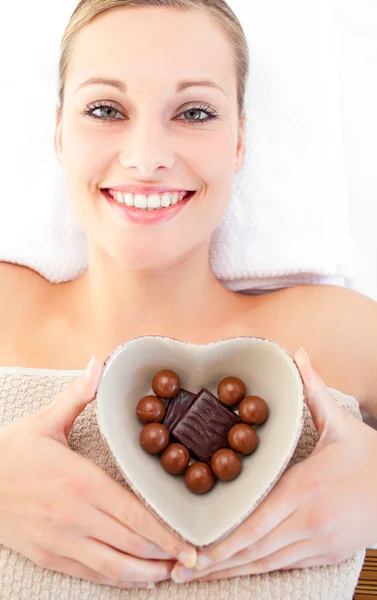 Веселая женщина держит миску в форме сердца с шоколадом — стоковое фото
