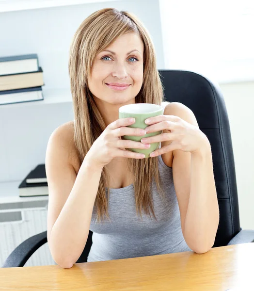 Mulher de negócios brilhante segurando uma xícara em sua mesa — Fotografia de Stock