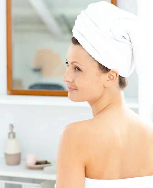 Positieve jonge vrouw met een handdoek invoering crème op haar gezicht in t — Stockfoto
