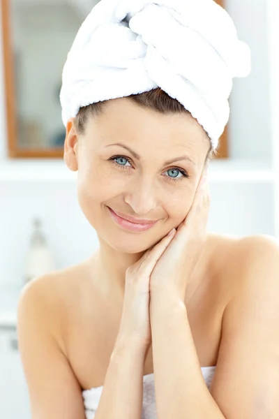 Mulher bonita com uma toalha colocando creme em seu rosto em — Fotografia de Stock