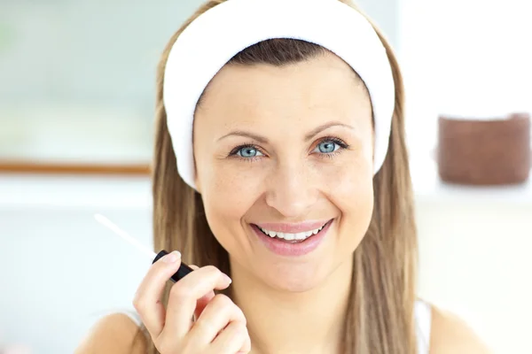 Позитивная женщина наносит блеск на губы в ванной комнате — стоковое фото
