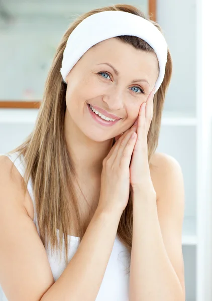 Sorridente giovane donna mettendo la crema sul suo viso in bagno — Foto Stock