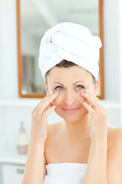 Krásná mladá žena s ručníkem dát krém na tvář — Stock fotografie