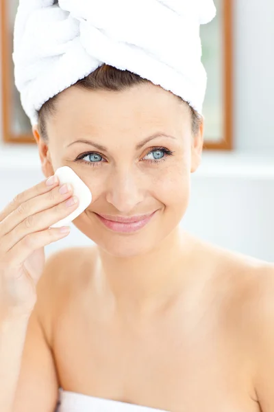 Bella giovane donna con un asciugamano mettendo crema sul viso nel — Foto Stock