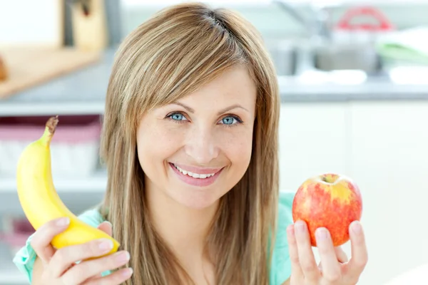Positive caucasian woman holing a banana and an apple in the kit — Stock Photo, Image