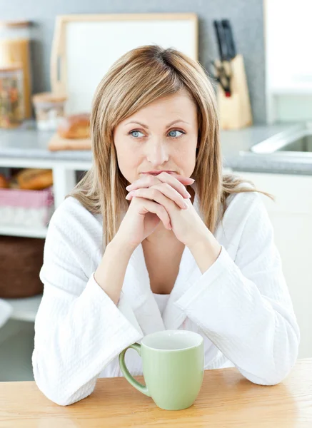 Tankeväckande kvinna med en kopp kaffe i köket — Stockfoto