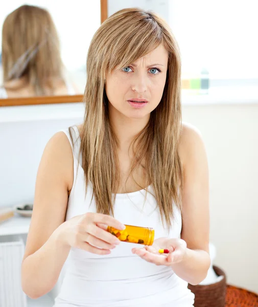 Болезненная женщина держит таблетки в ванной комнате — стоковое фото