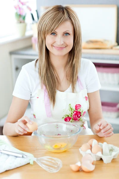 Joyeuse femme cuisine dans la cuisine et casser des œufs — Photo