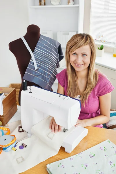 Positieve jonge vrouw naaien kleren thuis — Stockfoto
