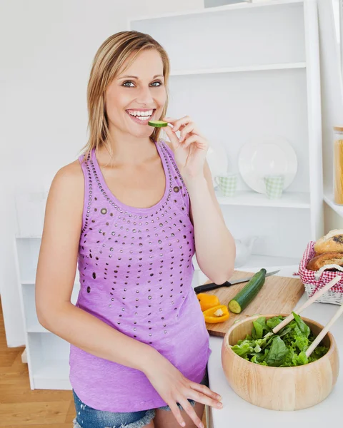 Gülümseyen kadın mutfakta salatalık yemeyi — Stok fotoğraf