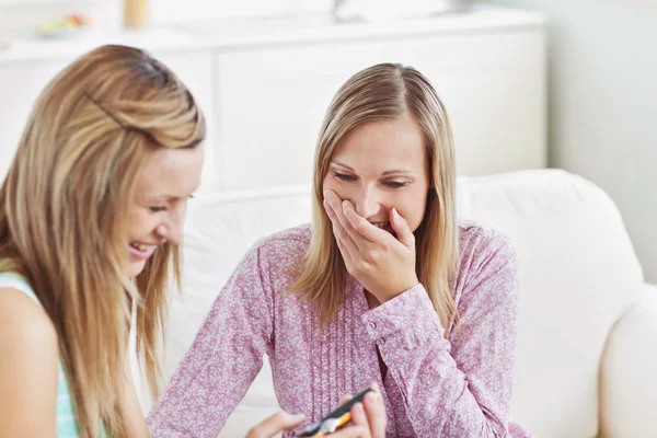 Due belle amiche che usano una macchina fotografica digitale su un divano — Foto Stock