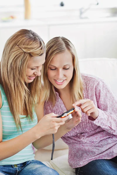 Sluit twee vrouwelijke vrienden met behulp van een digitale camera op een sofa — Stockfoto