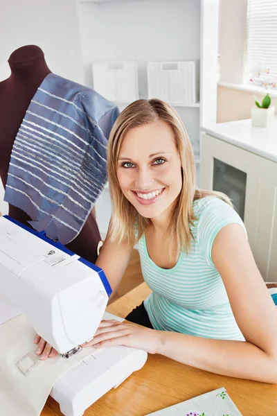 Stralende jonge vrouw naaien kleren thuis — Stockfoto