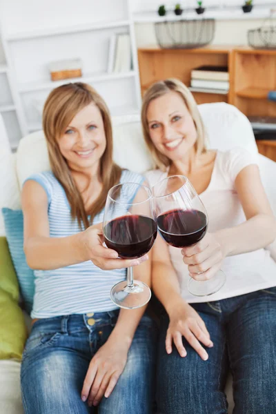 Dvě světlé ženy drží skleničku s vínem na pohovce — Stock fotografie