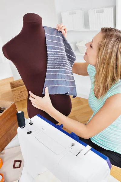 Mujer joven y seria cosiendo ropa en casa —  Fotos de Stock