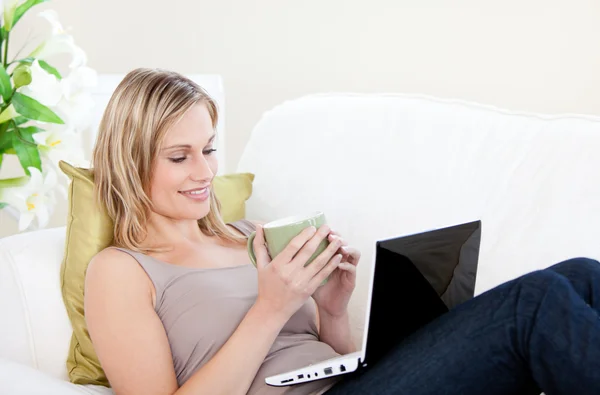 Onu laptop oturan ve bir fincan holding beyaz kadın — Stok fotoğraf