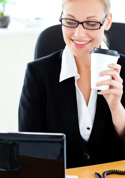 Mulher de negócios caucasiana radiante segurando um café usando seu lapto — Fotografia de Stock