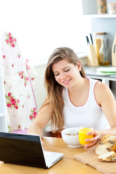 Entusiasta giovane donna che utilizza il suo computer portatile mentre fa colazione — Foto Stock